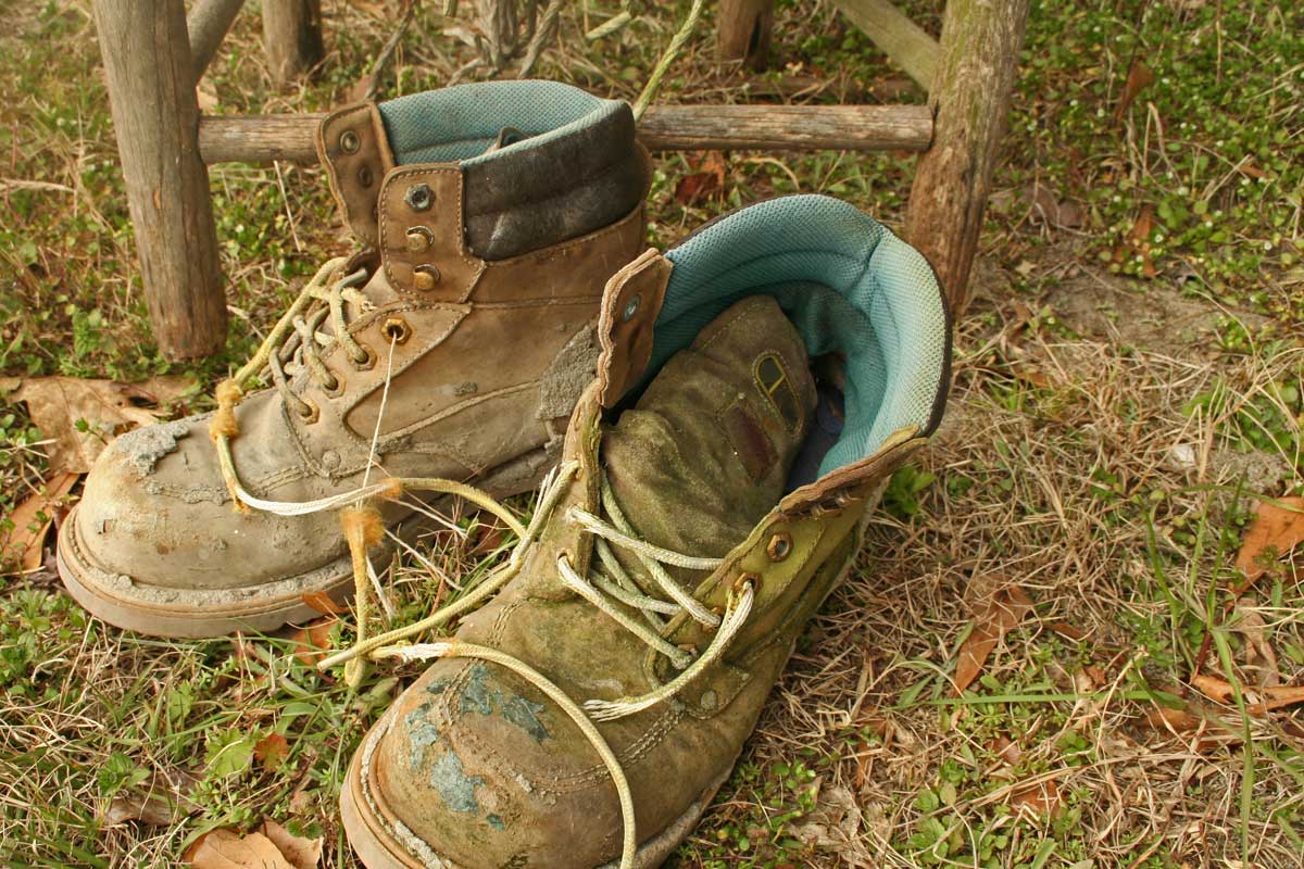 Alte Wanderschuhe auf vertrocknetem Gras einem Stuhl